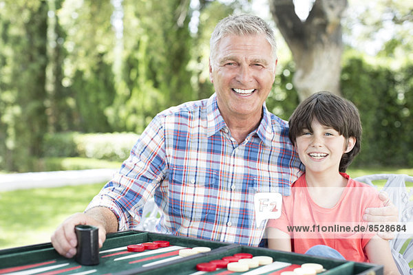 Großvater und Enkel spielen Backgammon auf der Terrasse