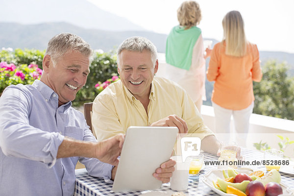 Senioren mit digitalem Tablett am Terrassentisch
