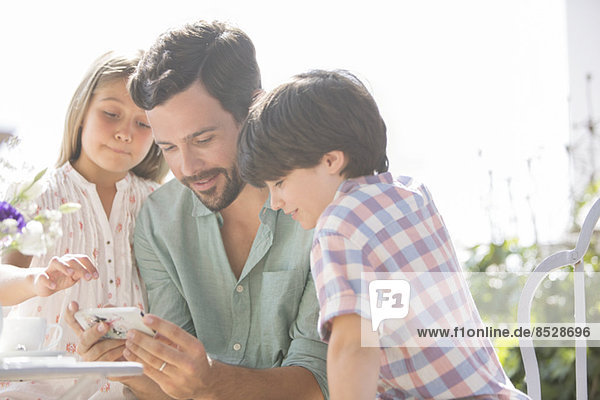 Vater und Kinder mit dem Handy im Freien