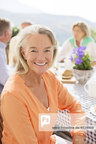 Seniorenfrau lächelt am Terrassentisch