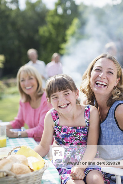 Mother and daughter laughing at table in backyard