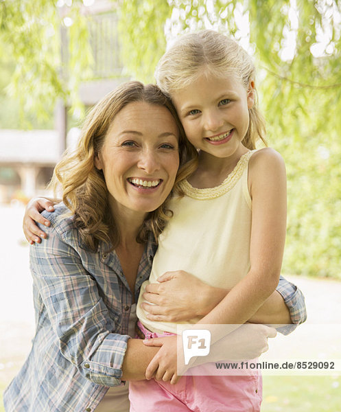 Mother and daughter hugging outdoors