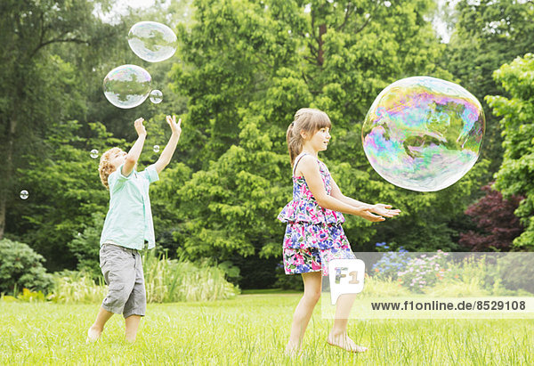 Kinder spielen mit Blasen im Freien