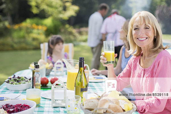 Smiling woman enjoying lunch at table in backyard