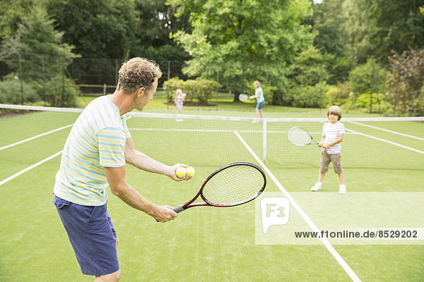 Family playing tennis on grass court