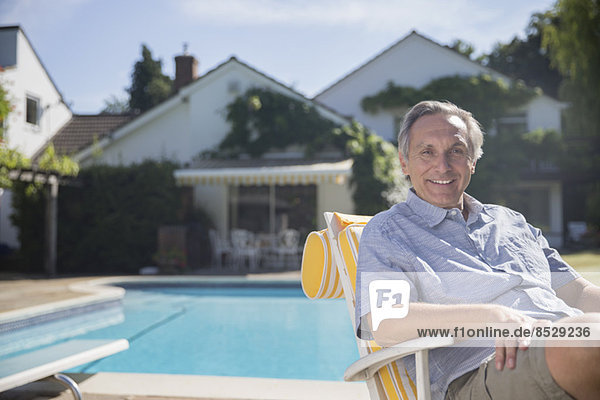 Smiling man in lounge chair at poolside