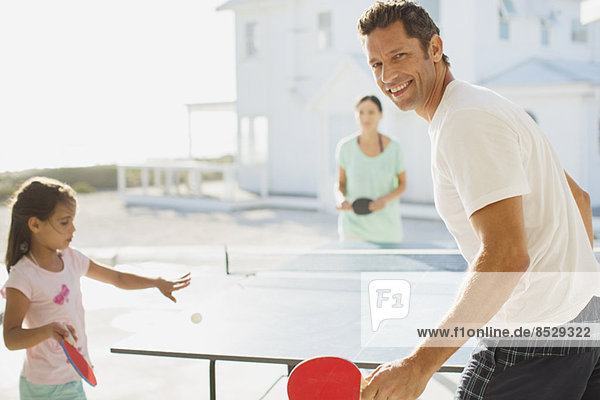 Familie spielt Tischtennis außerhalb des Hauses