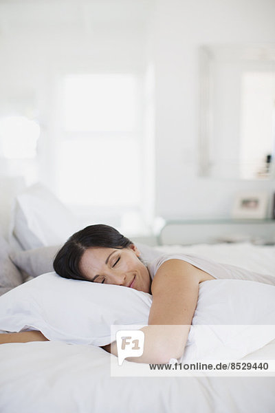 Woman hugging pillow on bed