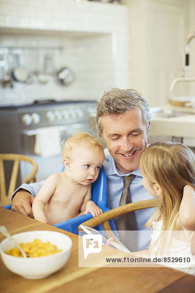 Vater im Gespräch mit Kindern beim Frühstück