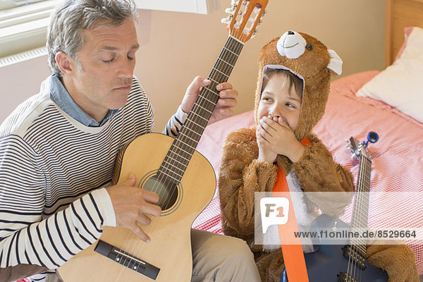 Vater und Sohn spielen zusammen Gitarre