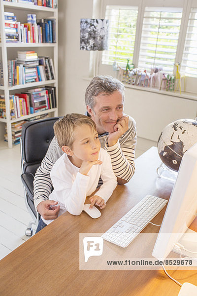 Vater und Sohn nutzen gemeinsam den Computer
