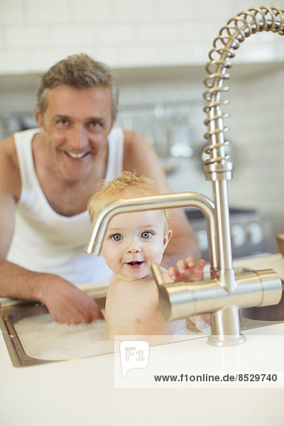 Vater badendes Baby in der Küchenspüle
