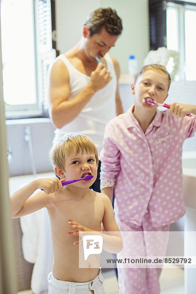 Vater und Kinder beim Zähneputzen im Bad