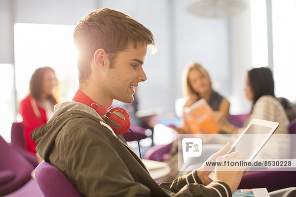 Universitätsstudent mit digitalem Tablett in der Lounge