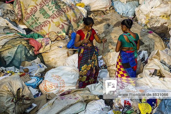 Zwei Frauen in bunten Saris beim Aussortieren von Müll zum Recycling  Dharavi Slum  Mumbai  Maharashtra  Indien