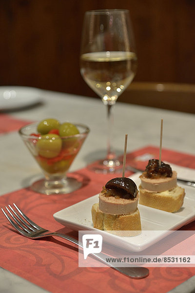 Leberpastete mit karamelisiertem Kürbis auf Weißbrot  grüne Oliven  und Weißwein in einer Tapas-Bar  Palma  Mallorca  Balearen  Spanien