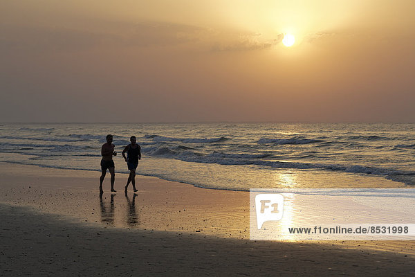 Zwei Männer laufen im Sonnenuntergang am Strand  Silhouette  Al-Batina Provinz  Oman  Arabische Halbinsel