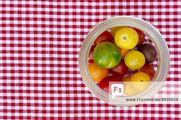 Frische Heirloom Tomaten in Einmachglas auf karierter Tischdecke