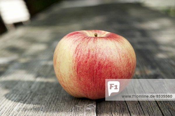 An apple on a wooden table in the garden