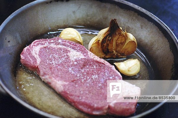 Steak vom Angusrind mit Knoblauch in der Pfanne