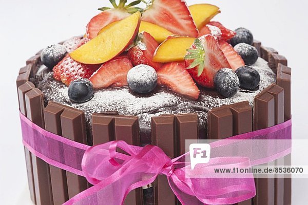 Schokoladentorte mit frischen Früchten  Puderzucker und rosa Schleife