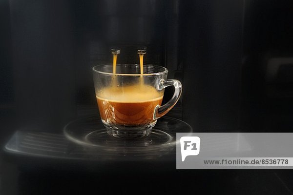 Kaffee fliesst aus der Espressomaschine in eine Glastasse