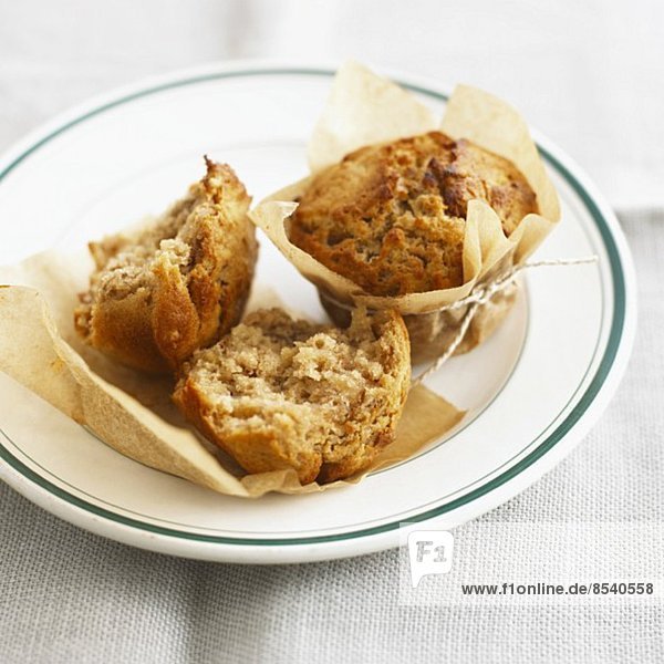 Apple and walnut muffins in baking parchment on a plate
