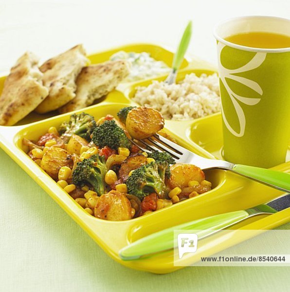 Vegetable curry with rice and a drink on a canteen tray