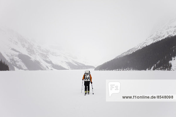 Ein Skifahrer überquert einen zugefrorenen See auf der Wapta Traverse  einer Skitour von Hütte zu Hütte in Alberta  Kanada.