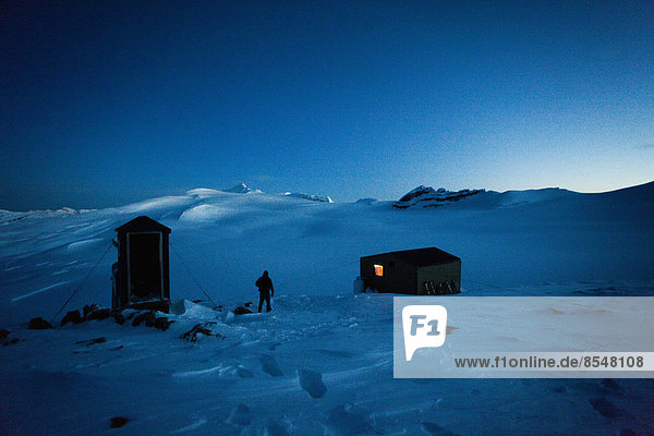 Eine Schutzhütte auf der Wapta-Traverse  eine 4-tägige Skitour von Hütte zu Hütte. Ein Skifahrer verlässt die Haupthütte  um die Toilette des Nebengebäudes zu benutzen.