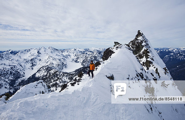 Ein Skifahrer auf einem Bergkamm  der vor dem Skifahren pausiert The Slot on Snoqualmie Peak in den Cascades Ranges  Bundesstaat Washington  USA.