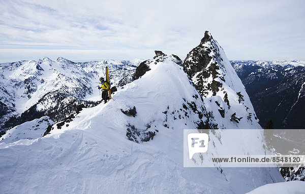 Ein Skifahrer steht auf einem Grat,  bevor er auf dem Slot auf dem Snoqualmie Peak in der Cascades Range im Bundesstaat Washington,  USA,  Ski fährt.