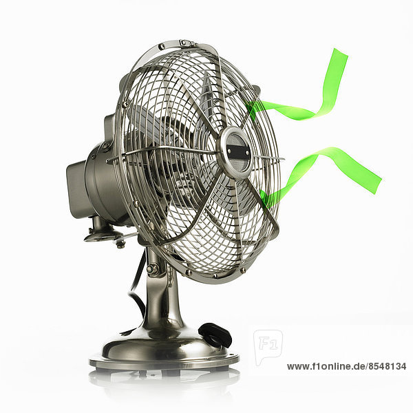 Ein elektrischer Ventilator mit Schutzkäfig um die beweglichen Teile und grüne Luftschlangen  die in der Brise wehen.