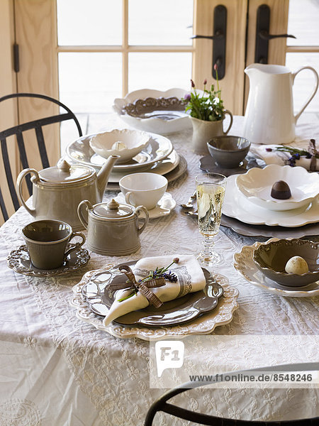 Ein für eine Mahlzeit gedeckter Tisch  mit einer weißen Tischdecke und traditionellem weißen Porzellan  Tischservietten und Besteck.
