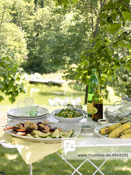 A buffet table set up in a garden for al fresco meal. Salads and prepared food dishes.