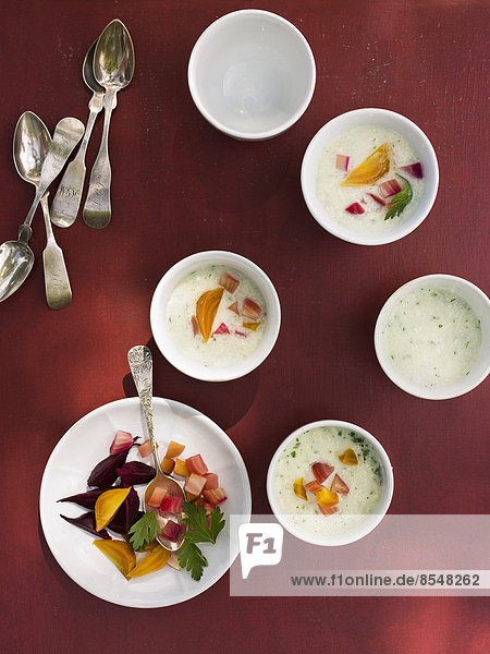 A table laid with small round white china bowls. Fresh food on a red background.