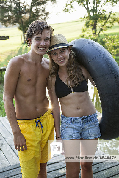 Young teenagers  boy and girl on a jetty by a water pool  holding a swim float.