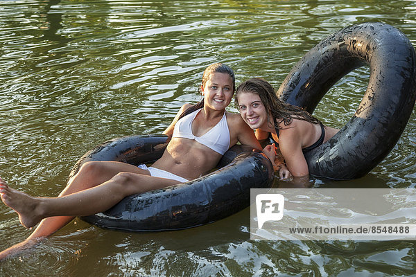 Zwei Mädchen schwimmen und schweben mit Schwimmflossen und aufgepumpten Reifen.