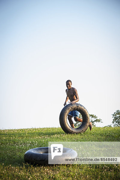 Ein Teenager  der über das Gras rennt und einen Schwimmwagen rollt  vor ihm ein schwarzer Reifen.