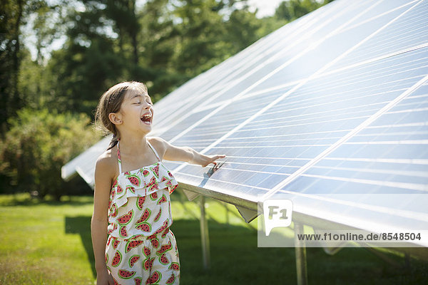 Ein Kind an der frischen Luft an einem sonnigen Tag  neben Sonnenkollektoren auf einem Bauernhof im Staat New York  USA.