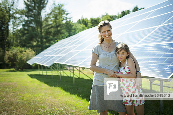 Ein Kind und seine Mutter an der frischen Luft  neben Sonnenkollektoren an einem sonnigen Tag auf einer Farm im Staat New York  USA.