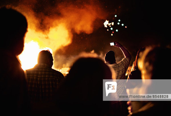 Silhouettes of people around a large bonfire.