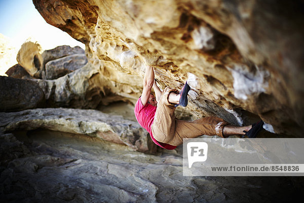 Ein Mann  der am Überhang einer Felswand frei klettert  mit minimaler Ausrüstung.