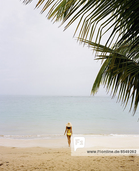 Eine junge Frau in einem gelben Bikini an einem Strand auf der Halbinsel Samana in der Dominikanischen Republik.