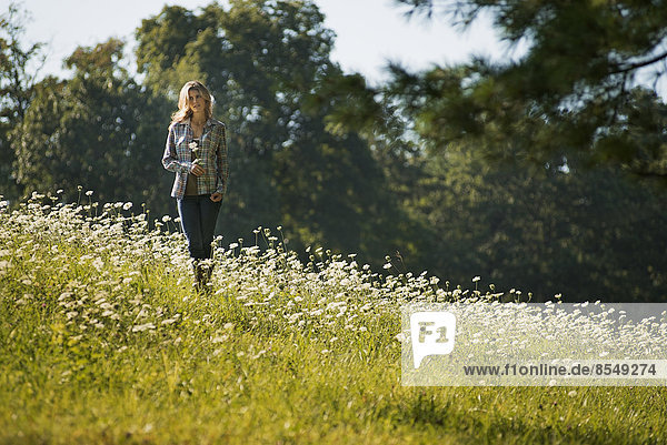A young woman walking in a wild flower meadow.