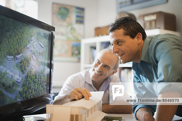 Two architects working on a green construction project  using computer technology. Scale model of a building. Computer design.
