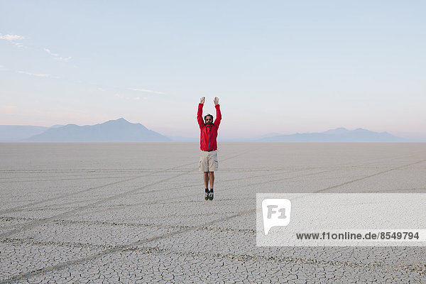 A man jumping in the air on the flat desert or playa or Black Rock Desert  Nevada.