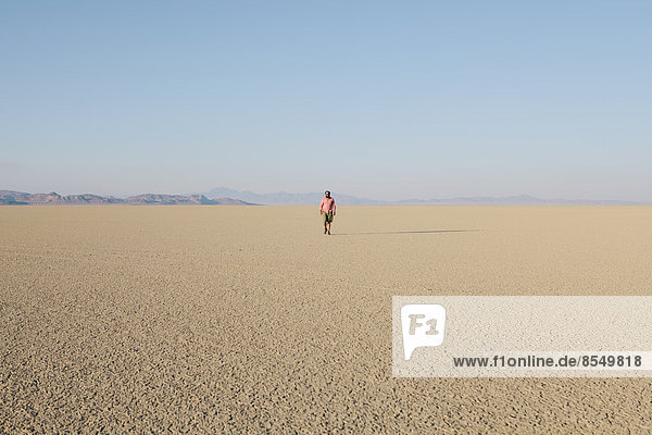 Man walking across a flat desert landscape
