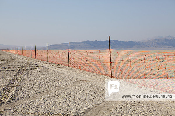Zaunbarrikade  die sich über die flache Landschaft erstreckt  Black Rock Wüste  Nevada  USA