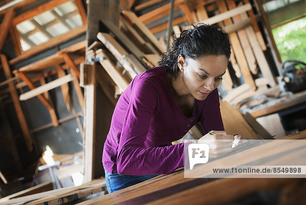 A woman working with reclaimed timber in a woodwork workshop.